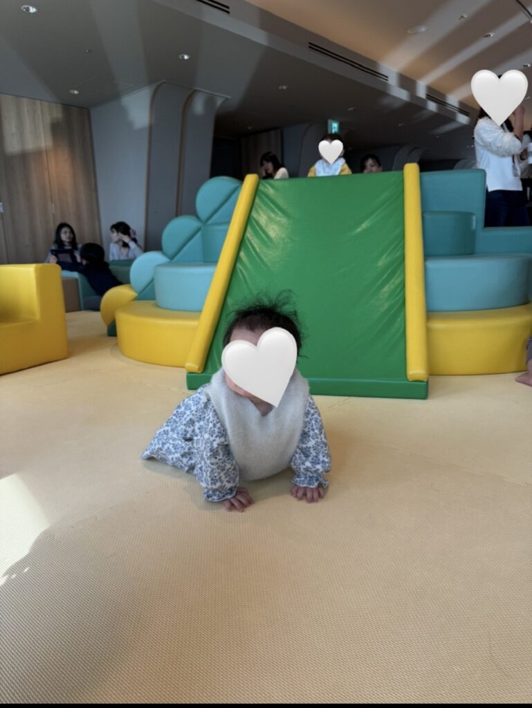 新宿の京王プラザホテル47階「SKY PLAZA IBASHO」の室内遊び場で、クッション遊具の前に座る赤ちゃん。安全な床素材の広いプレイスペース。